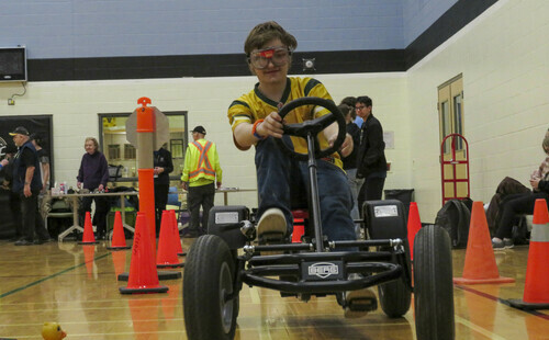 Student riding a pedal kart along an obstacle course