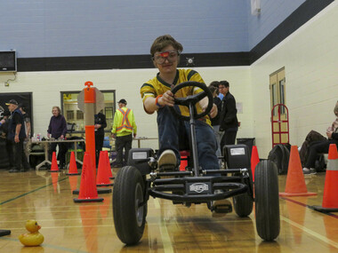 Student riding a pedal kart along an obstacle course